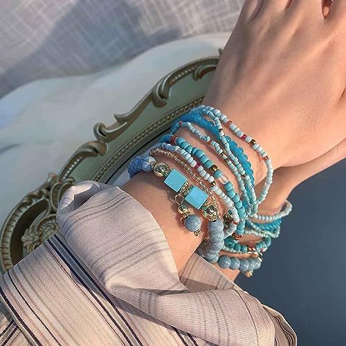Bracelet fantaisie multicouche pour femme, perles et pompons, accessoire tendance, adaptable à tous les styles et occasions, polyvalent et élégant.
