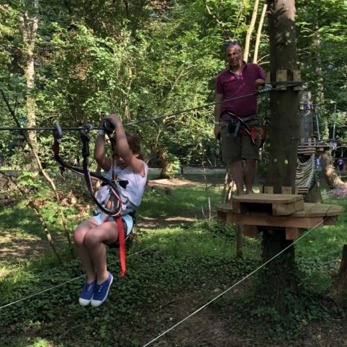 Personnes s'amusant en accrobranche, traversant ponts suspendus et tyroliennes, activité nature idéale pour tous âges, cadeau aventureux et sécurisé